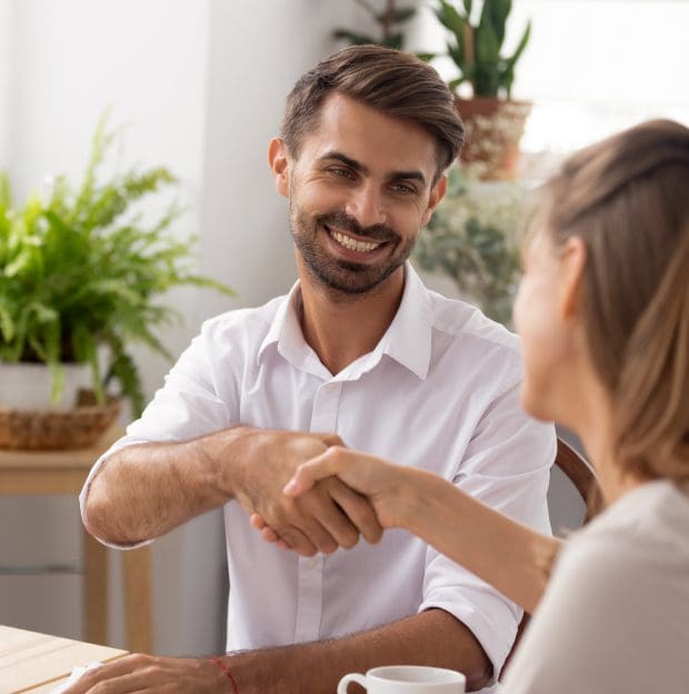 Two people shaking hands, smiling, indoors.